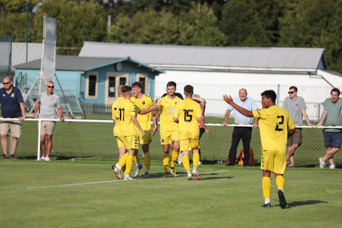 Tadley players rush to celebrate with Andrew Charsley (centre) after his winning goal against Fawley sent them through to the first qualifying round of the FA Cup for the first time. Credit: Elisha Bootham Photography.