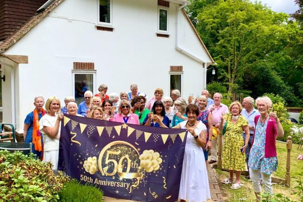 Winchester Women Graduates holding 50th anniversary banner in president Reefat Drabu's garden